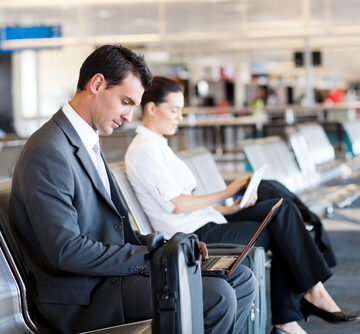 Businessman,And,Businesswoman,Using,Laptop,And,Tablet,Computer,At,Airport BUSINESS TRAVEL SLOWING