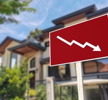 A sign showing a downward arrow in front of a house