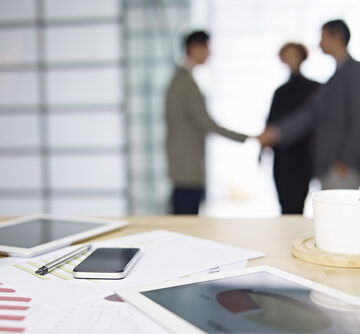 Close-up of business items with people meeting in background.