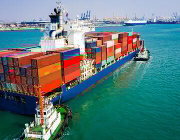 Container Ship Sailing into port with tugboat