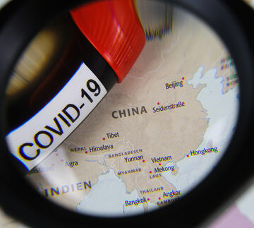 View of map and Covid-19 label through magnifying glass