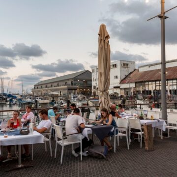 Waterside Street Cafe With Many Guests At The Tables