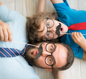 Funny Man And Kid With Fake Mustaches Playing