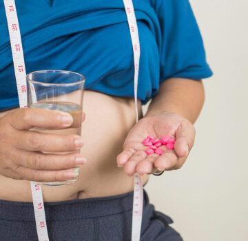 Woman Measuring Her Waist With Many Slim Pills In Her Hand