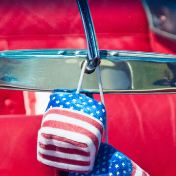 Stars and Striped dice hanging off a rear-view car mirror