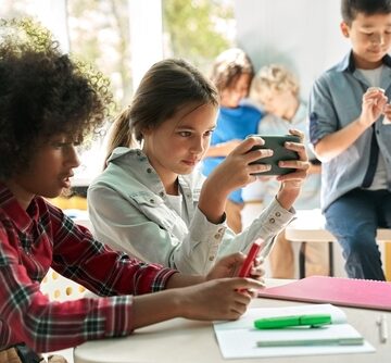 Diverse Group Of Children In Classroom Using Smartphones