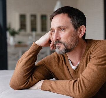Depressed Middle-aged Man Staring Out Of The Window