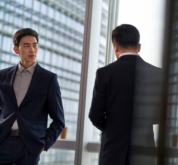 Two,Asian,Business,People,Colleage,Standing,By,The,Window,Talking SPOTLIGHT: CHINA’S ECONOMIC STRUGGLE