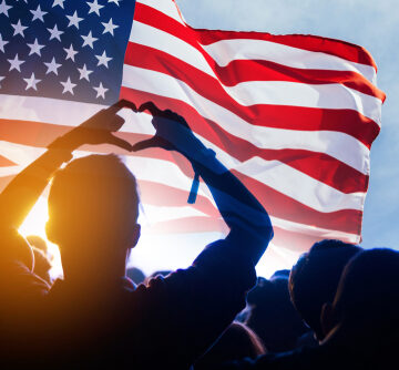 Cheering Crowd And The American Flag With Person Making Heart Sign With Their Hands
