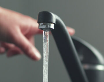 A hand Moving Handle and Water Pouring From Faucet