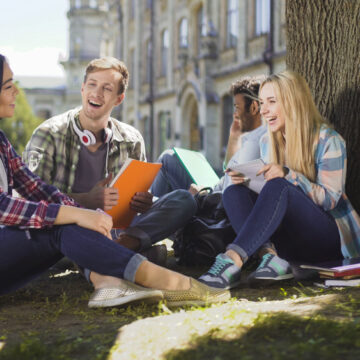 Group,Of,Friends,Sitting,Under,Tree,Talking,To,Each,Other Group Of College Students Sitting Under Tree Talking To Each Other