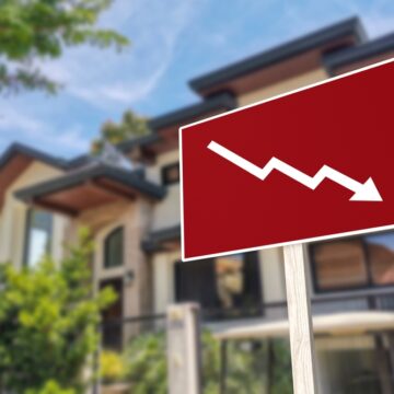 A Sign In Front Of A House Showing A Downward Arrow