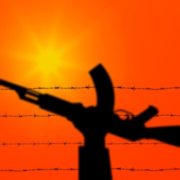 Palestine And Israel Conflict Represented By Hand Holding Gun Over Barbed Wire