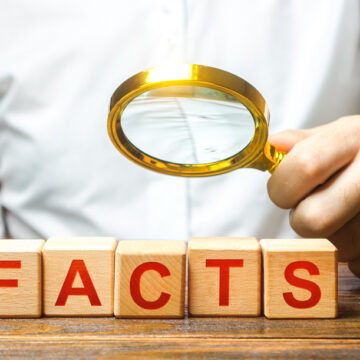 Man Examines Blocks With The Word Facts With A Magnifying Glass