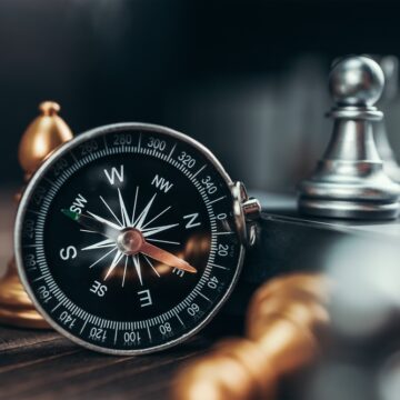 Compass And Chess Pieces On Chess Board Game