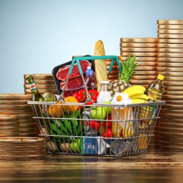 Inflation Growth Represented by A Basket of Food Surrounded By Rising Stacks Of Coins