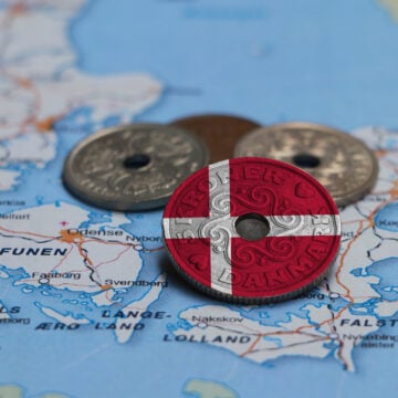 Denmark Flag And Map With Heap Of Danish Kroner Currency On Top