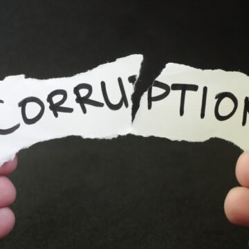 Hands Tearing Up A Piece Of Paper With The Word Corruption