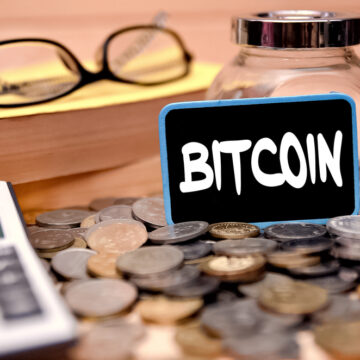 The Word Bitcoin On A Mini Chalkboard With Coins And A Calculator