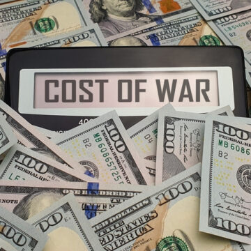 Piles Of U.S. Currency Surrounding Signs That Reads "Cost Of War"