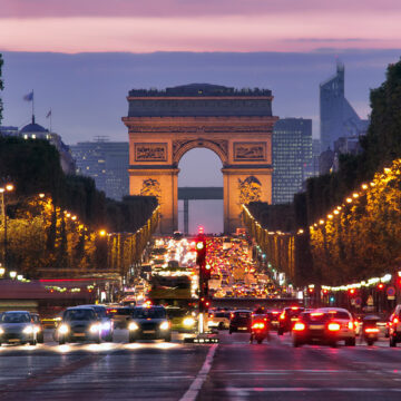 The Arc de Triomphe And Busy Traffic On The Champs-Elysees In Paris At Night