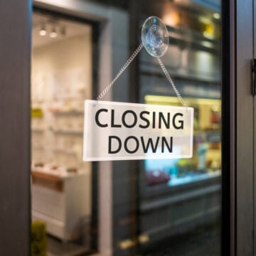 Closing Down Sign Painted On The Window Of A Dress Shop