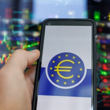ECB Logo On Mobile Phone Screen With Rate Graphs In Background