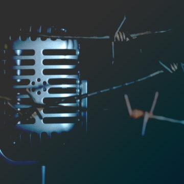Microphone Behind Barbed Wire Representing Stifling Of Free Speech