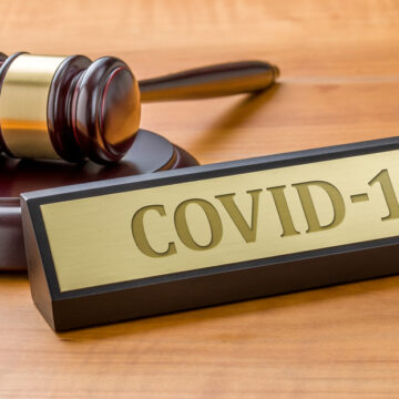 A Judge's Gavel And Desk Sign That Says Covid-19