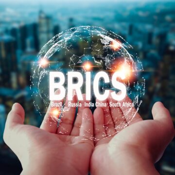 Two Hands Holding Globe With The Word BRICS on it.