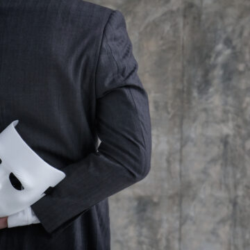Back Of A Businessman Holding A White Mask In His Hand