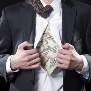 Concept Photo For Hidden Money Showing A Businessman Pulling Open His Shirt And Money Spilling Out