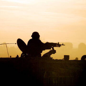 Silhouette Of Military Soldier On Army Tank On Battlefield