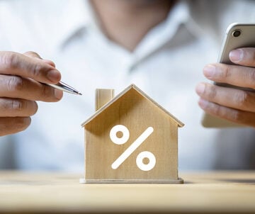 Person With Pen And Calculator Considering Property Interest Rate