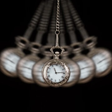 A Silver Pocket Watch Swinging On A Chain As If To Hypnotise