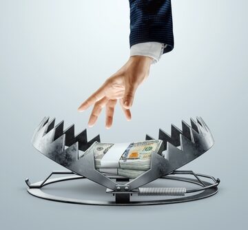 A Man's Hand Reaching To Take Dollars From A Bear Trap