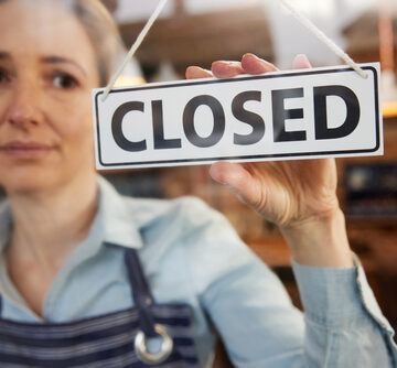 Female Small Business Owner Turning Around Closed Sign On Door