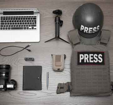Some Of The Equipment Necessary For The Work Of A Wartime Journalist–Vest, Helmet, Camera, Laptop, Microphone, Notepad