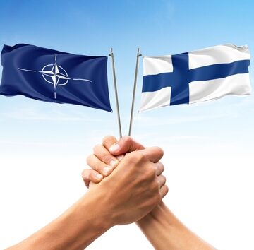Hands Holding Flags Of Finland And NATO