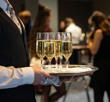 A Waiter Holding A Tray Of Champagne At Cocktail Party