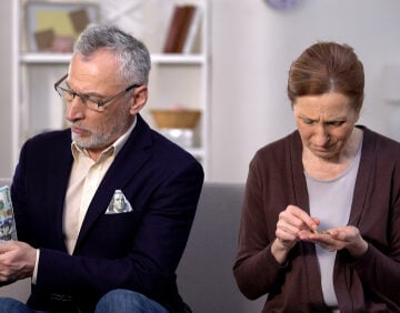 Rich Older Man Counting His Dollars Next To Poor Woman Counting Her Coins