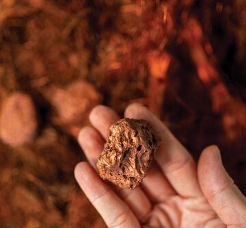 A Man's Hand Holding A Piece Of Copper Ore