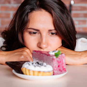 Woman Longingly Eyeing A Plate Of Desserts