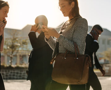 Men And Women Using Mobile Phones While Commuting To Office