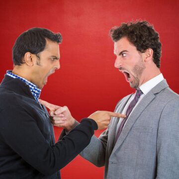 Two Men Pointing At Each Other And Arguing
