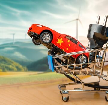 Shopping Cart With Chinese EV And Solar Wind Turbines In The Background