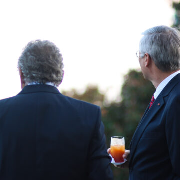 A Gathering Of Wealthy Man Having Cocktails On A Terrace