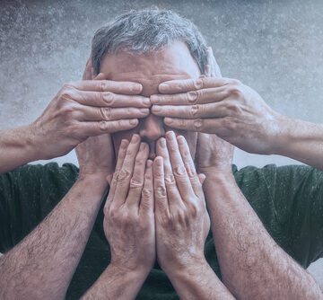 A MAn With His Eyes, Ears, And Mouth Covered As A Representation Of The Principle, "See No Evil, Hear No Evil, Speak No Evil."