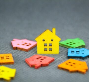 Colored Wooden Houses All Toppled Down Except For One In The Center