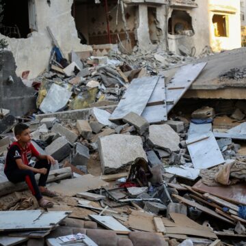 Palestinian Boy Sits Despondently Atop The Rubble Of Buildings Destroyed By An Airstrike